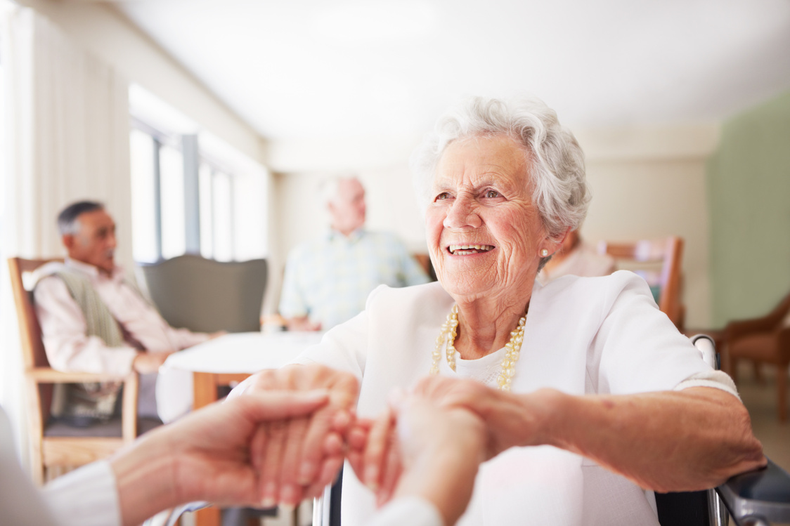 Nurse's hands hold elderly woman's at nursing home